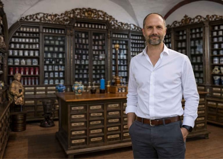 Ulrich Spindler im weißen Hemd in einer historischen Apotheke.