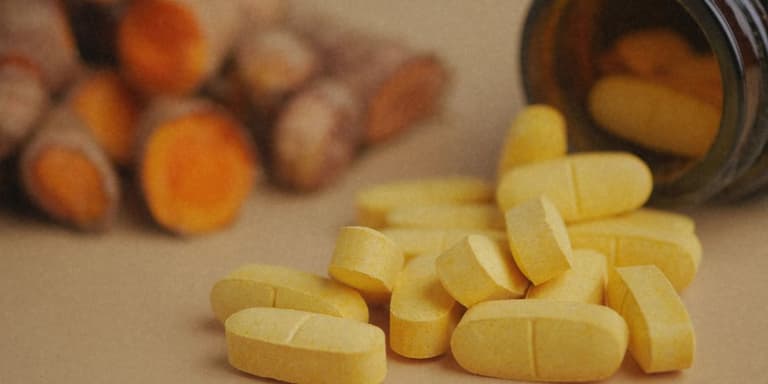 Curcumin Tabletten neben Curcumawurzeln.