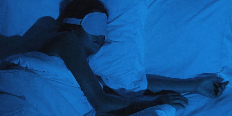 Eine Frau im Bett mit Schlafmaske.