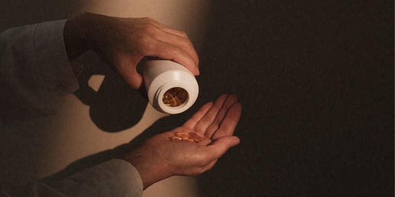 Pillen die aus einer Dose in eine Hand gekippt werden.